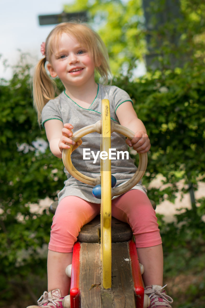 Full length portrait of smiling girl on seesaw at park