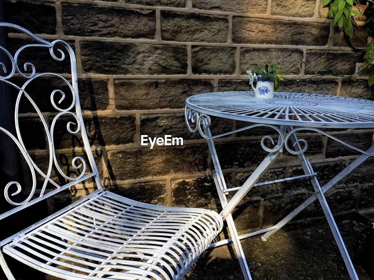 Metallic table and chair against wall in yard