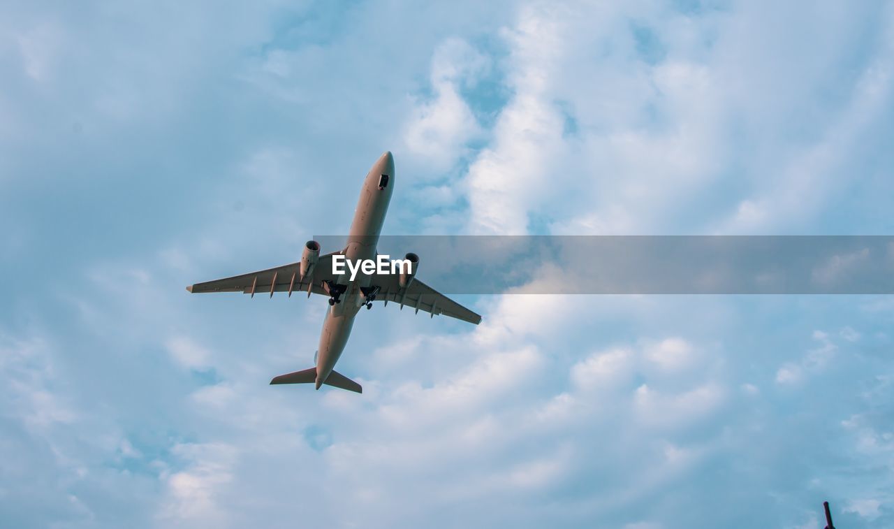 Directly below shot of airplane flying in cloudy sky