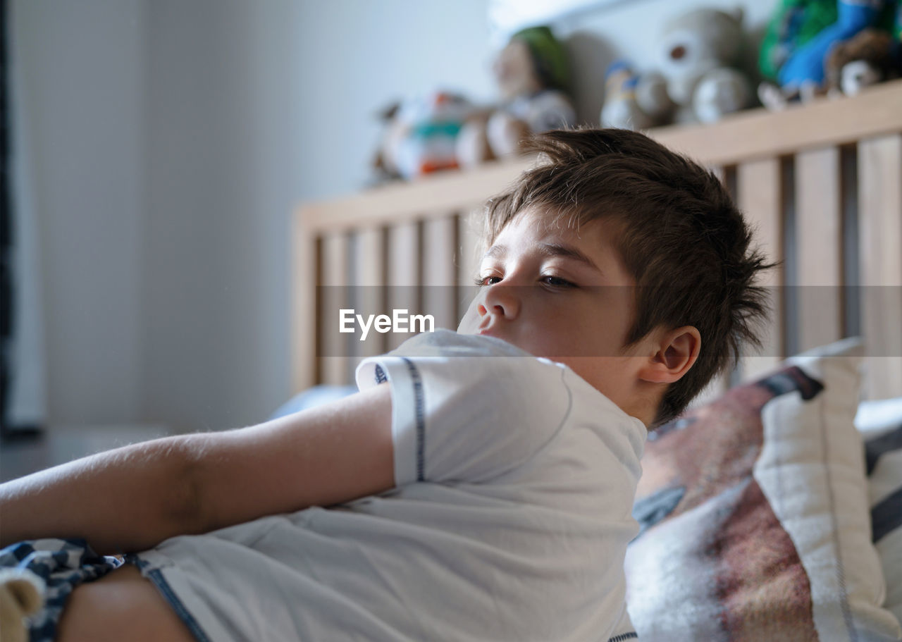 Cute boy lying on bed at home