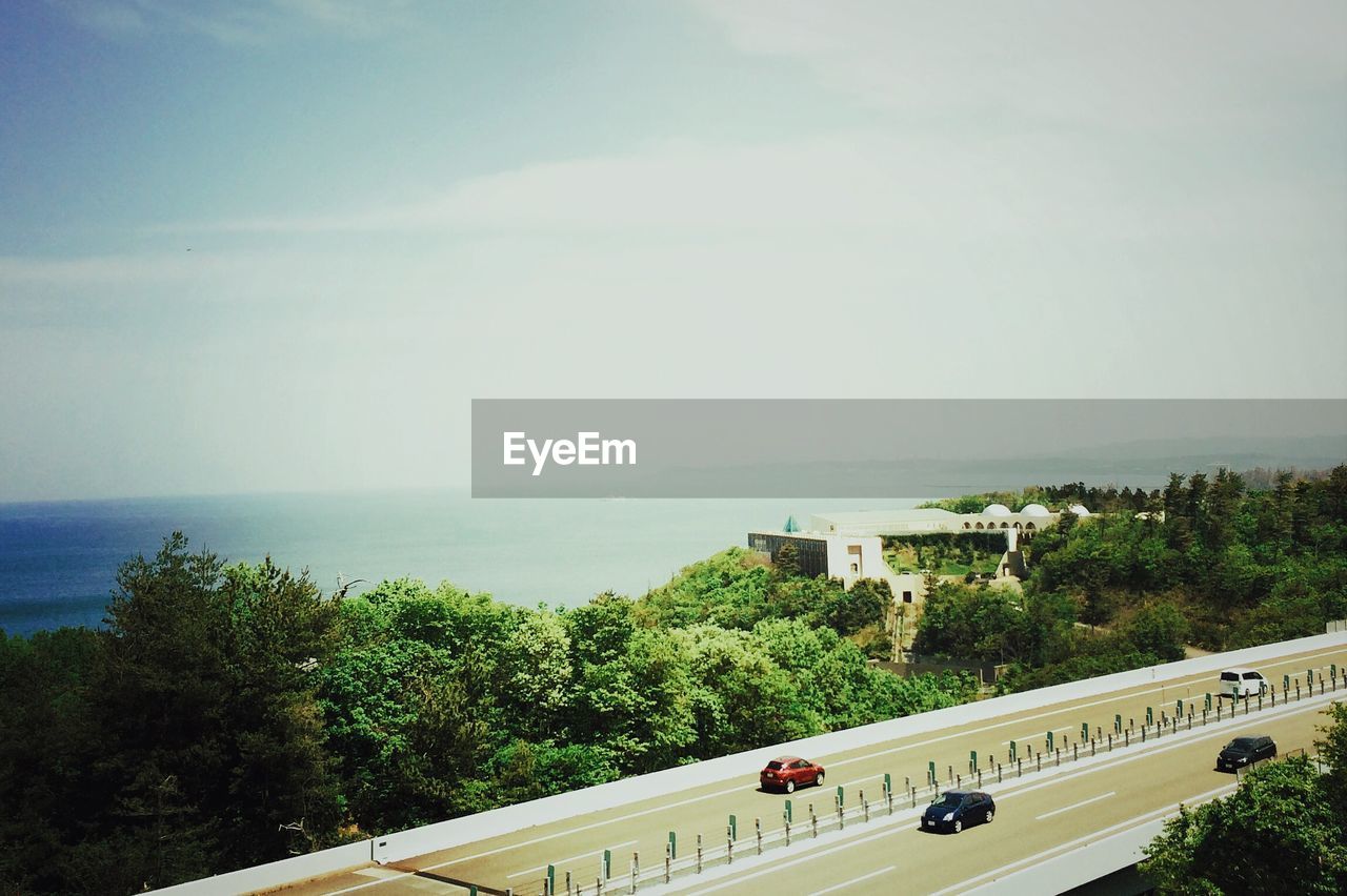 High angle view of cars on street by sea against sky