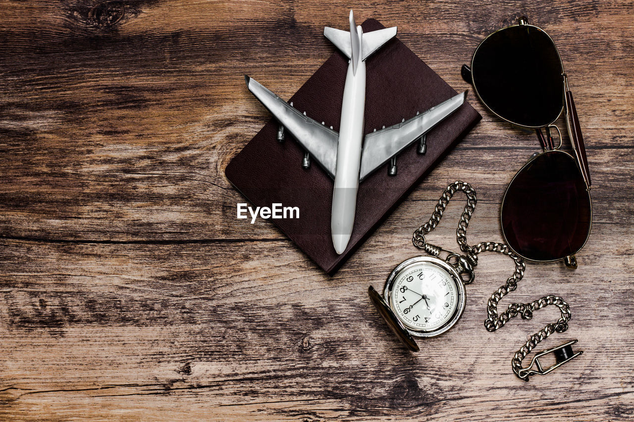 High angle view of model airplane with pocket watch on wooden table