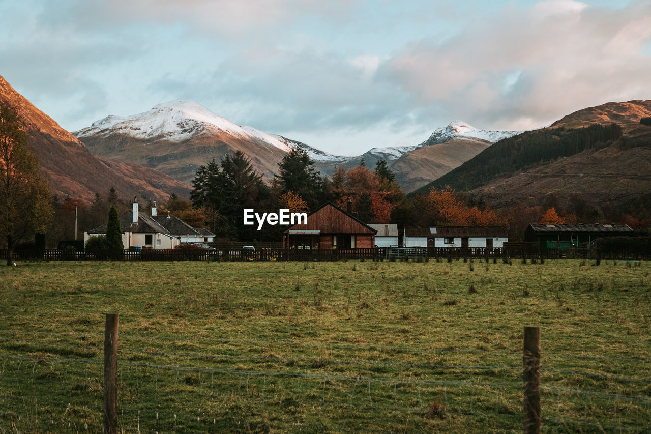 Houses on field by mountains against sky