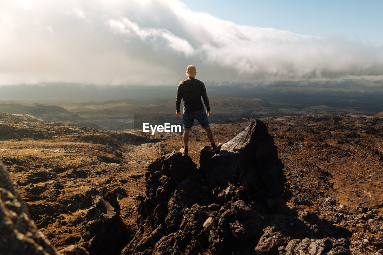 Full length of man standing on rock against sky