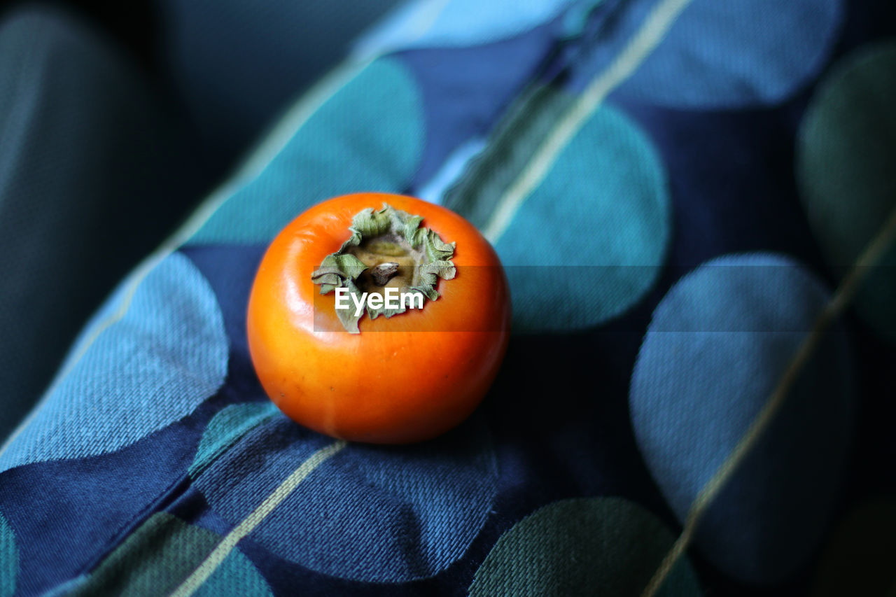 Close-up of persimmon on blue pillow 