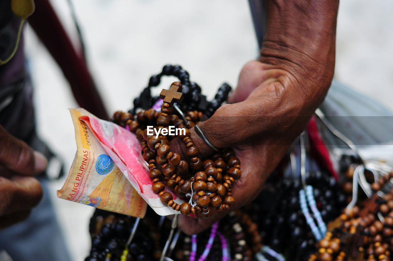 Close-up of vendor with money and rosaries