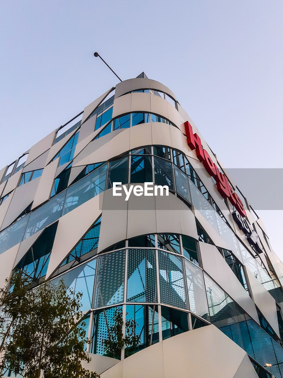 LOW ANGLE VIEW OF MODERN GLASS BUILDING AGAINST SKY