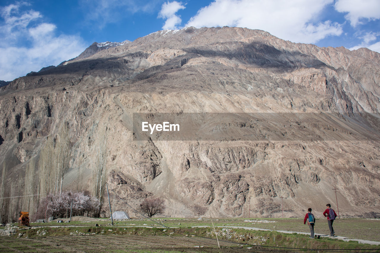 PEOPLE ON LANDSCAPE AGAINST MOUNTAINS