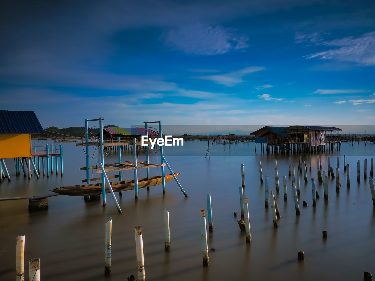 Wooden posts in lake against sky