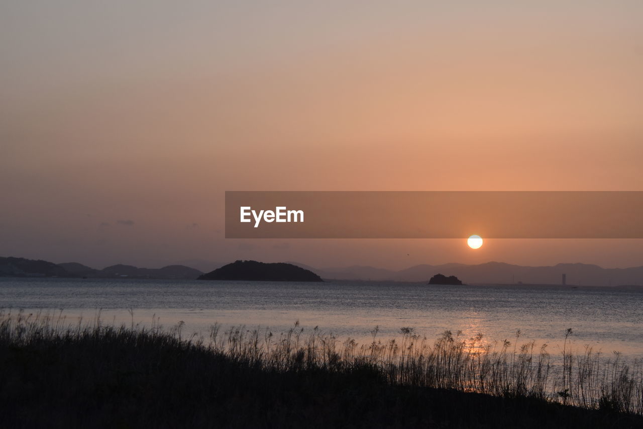 SCENIC VIEW OF LAKE AGAINST SKY AT SUNSET