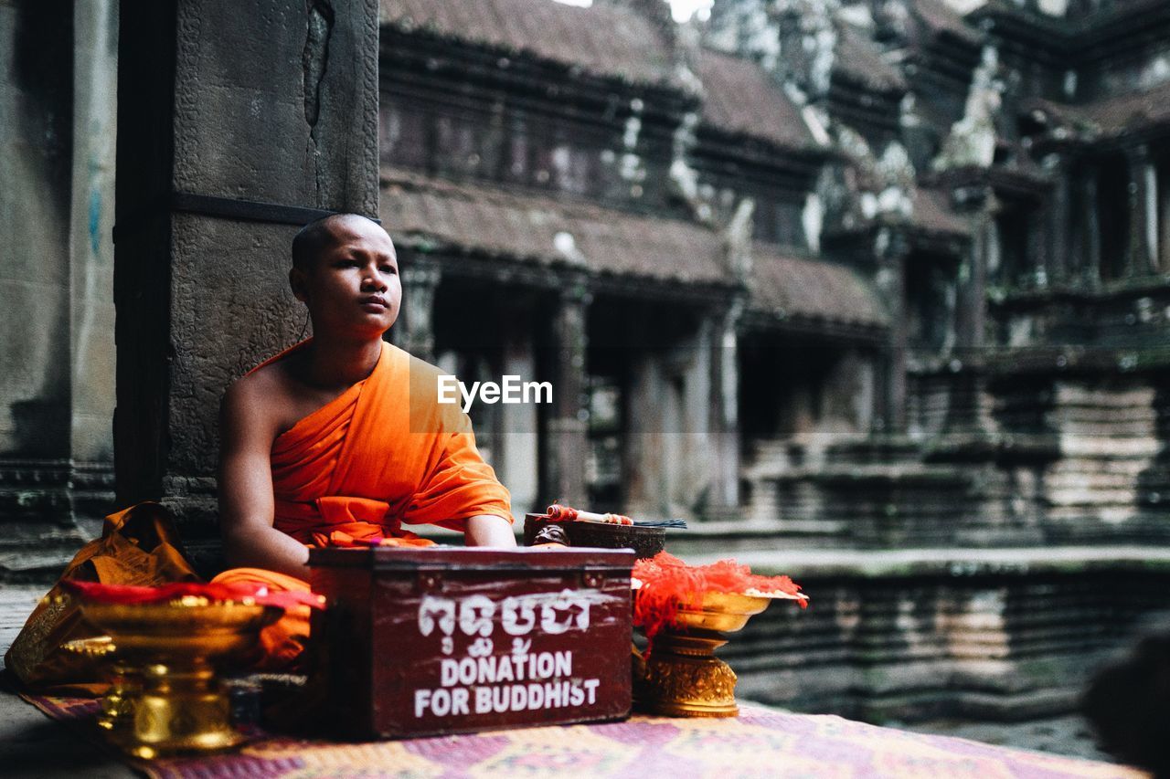 MAN LOOKING AT TEMPLE AGAINST BUILDING