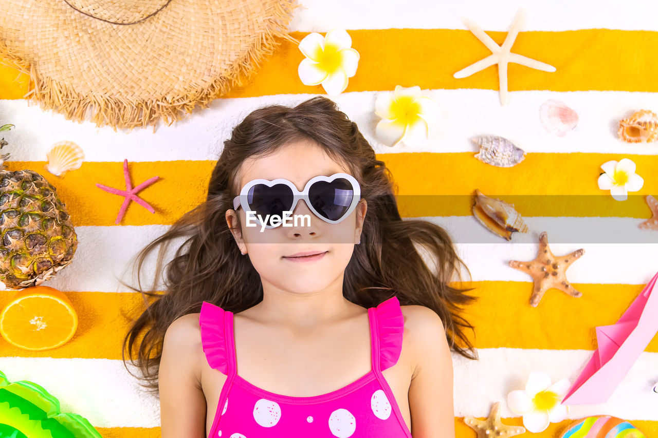 portrait of young woman wearing sunglasses while standing against yellow wall