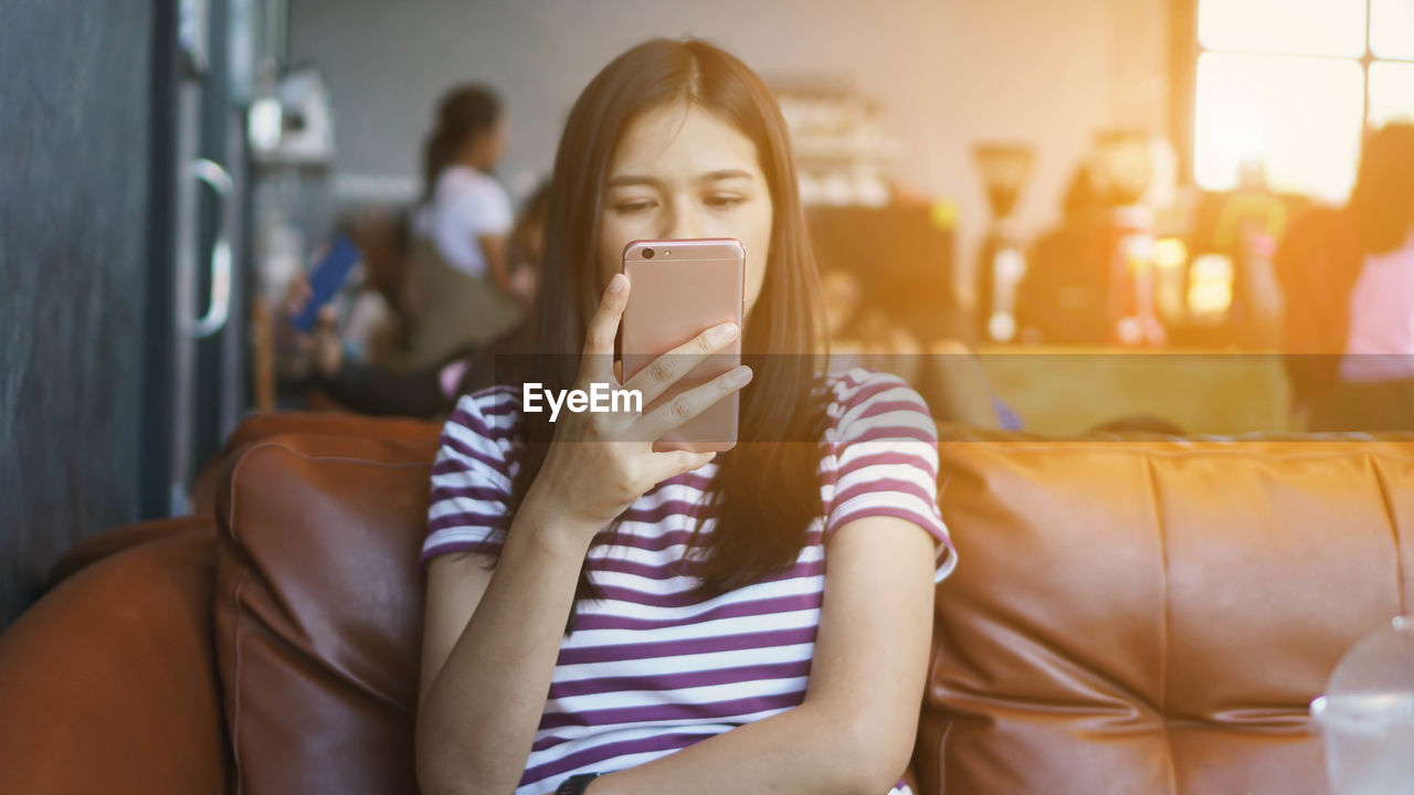 Young woman using smart phone sitting at cafe 