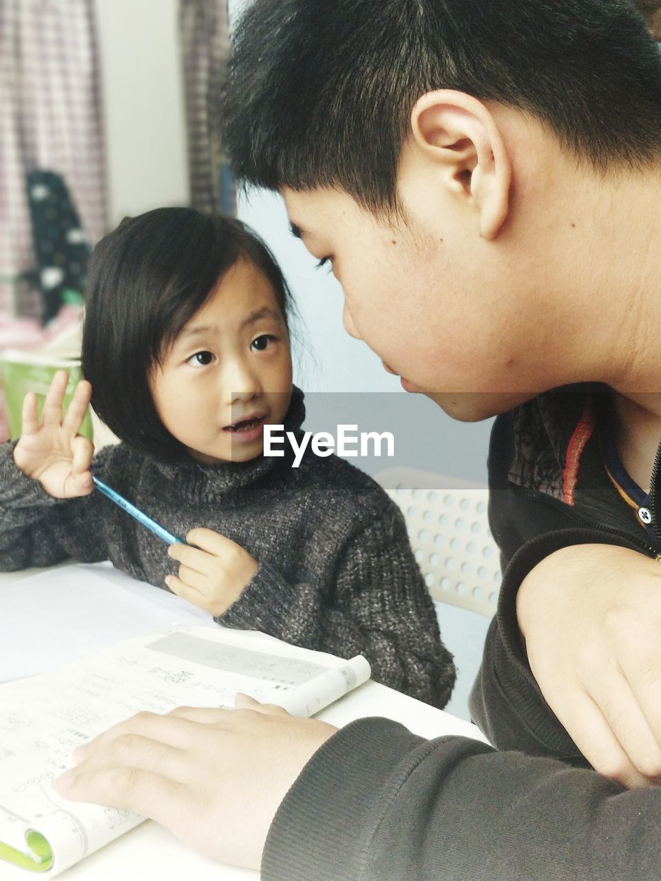 Teenage boy assisting sister in studying at home