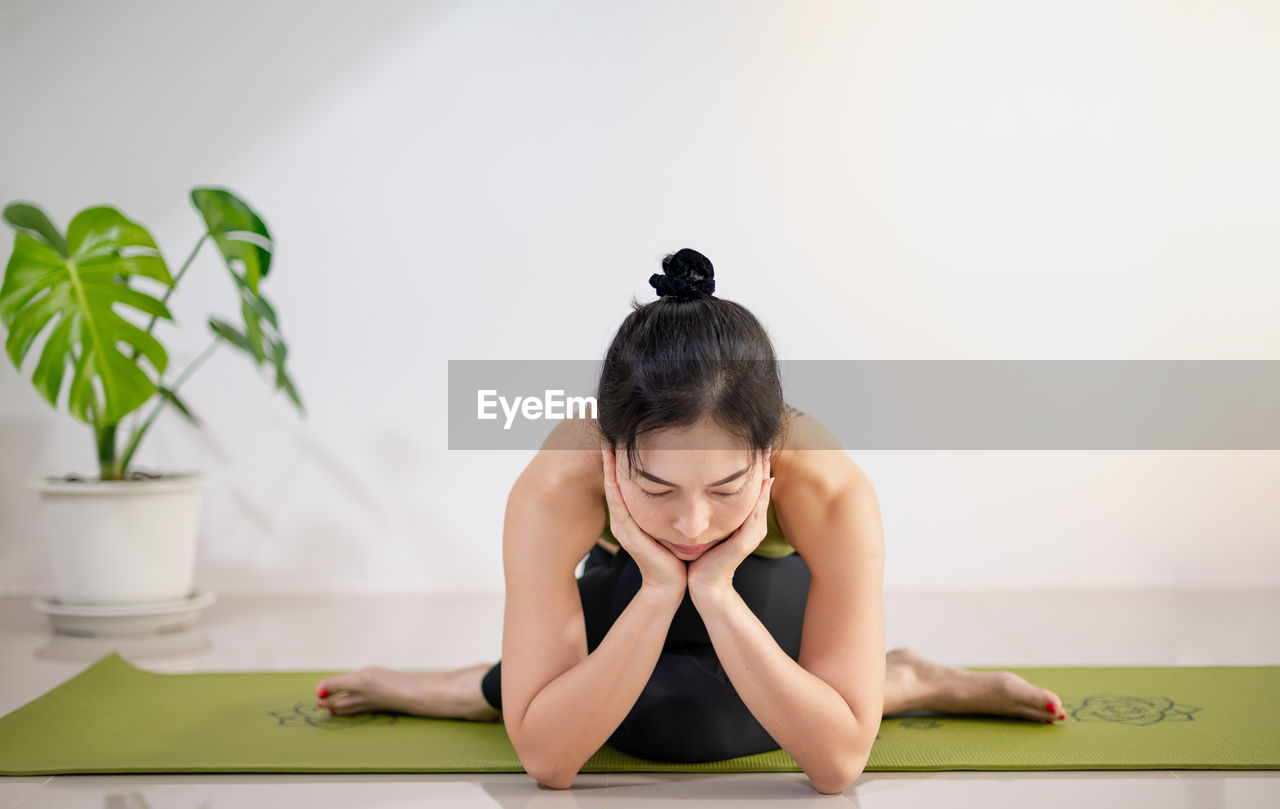 Woman doing yoga on the green yoga mat for meditite and excercise in the home.