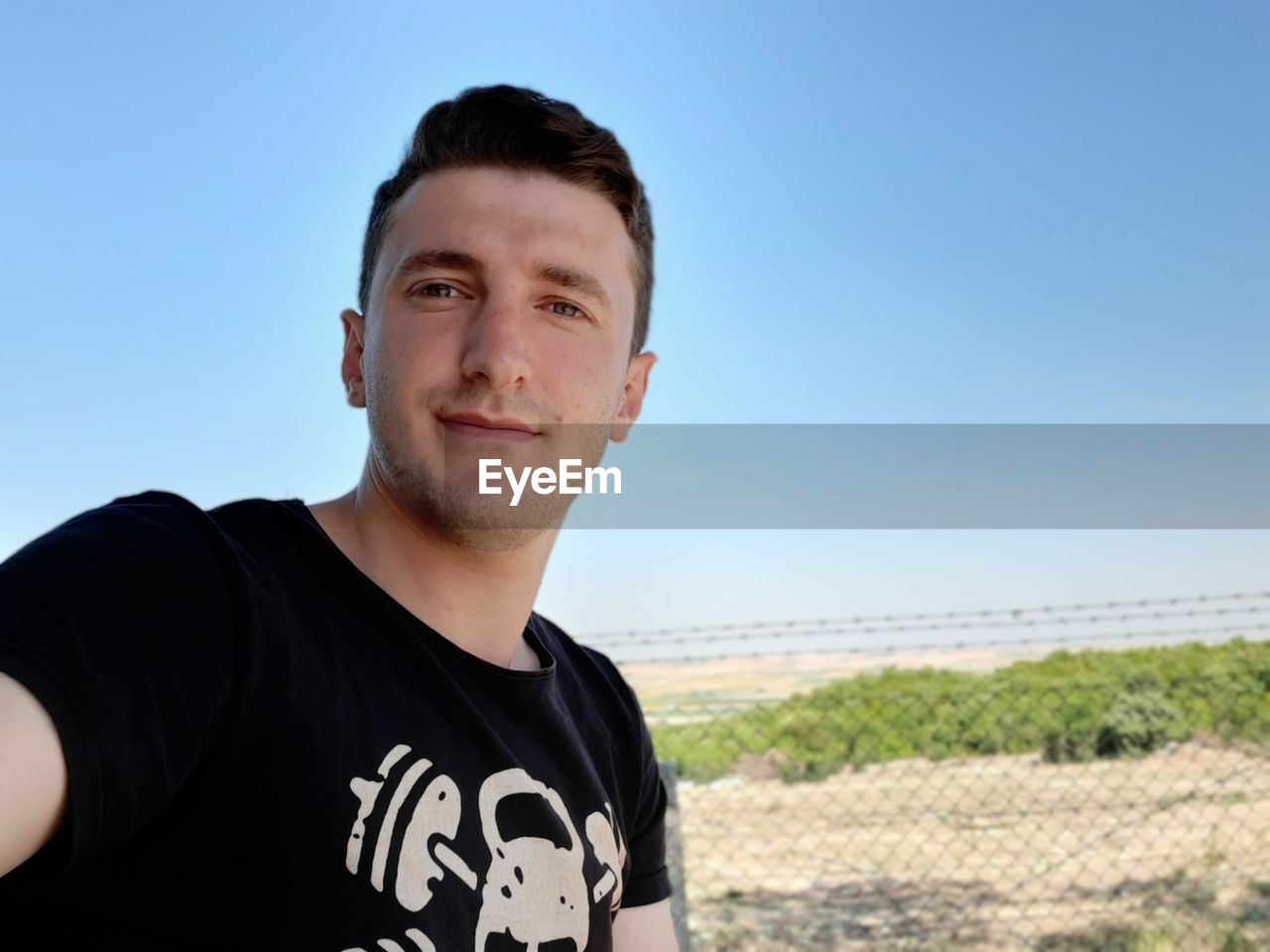 Portrait of young man standing against clear blue sky