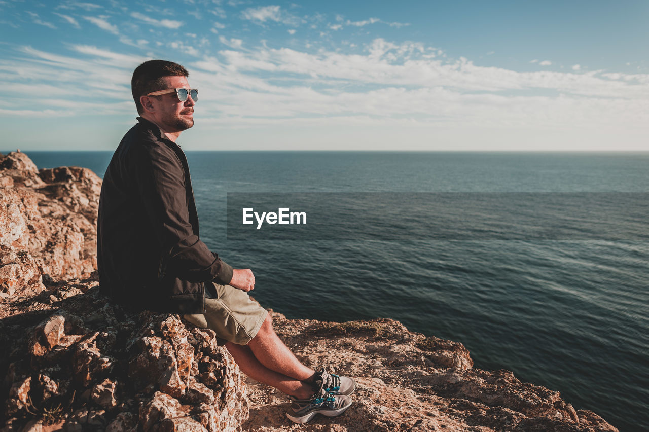 Young man looking out over ocean at sunset in portugal in summer