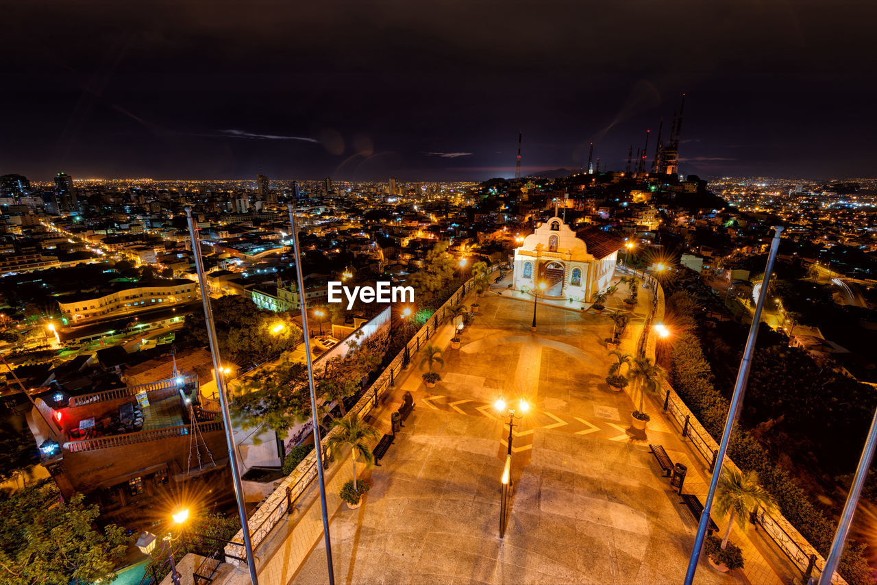 HIGH ANGLE VIEW OF ILLUMINATED STREET AMIDST BUILDINGS IN CITY