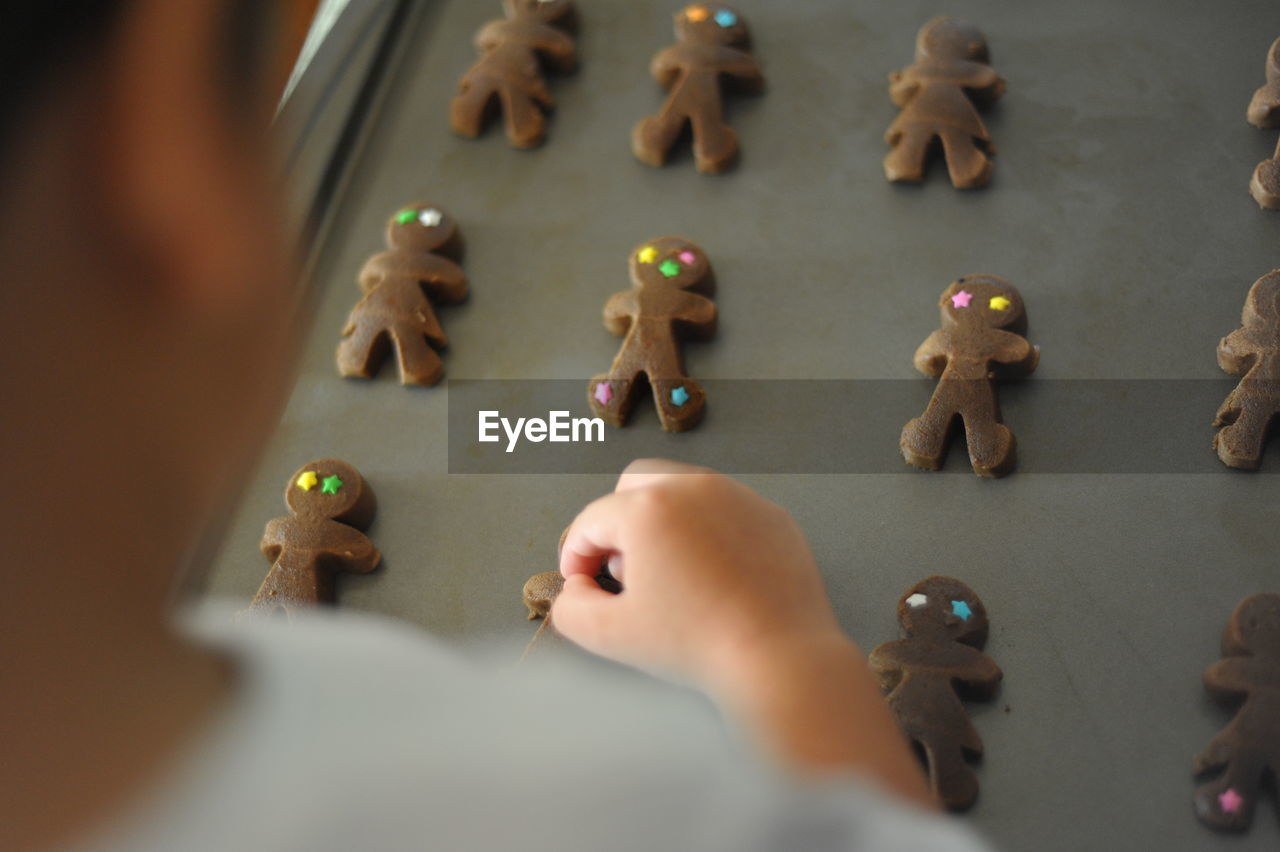 Cropped image of boy arranging gingerbread cookies on tray