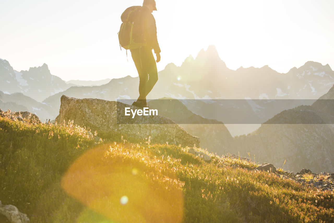 Side view of hiker backpacking across a high mountain range.