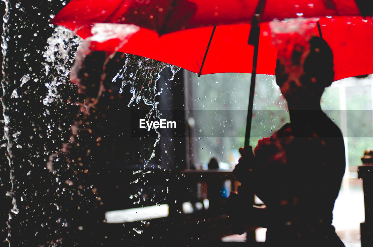 Woman with red umbrella during rainy season