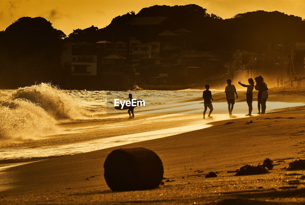 Silhouette of people on beach at sunset