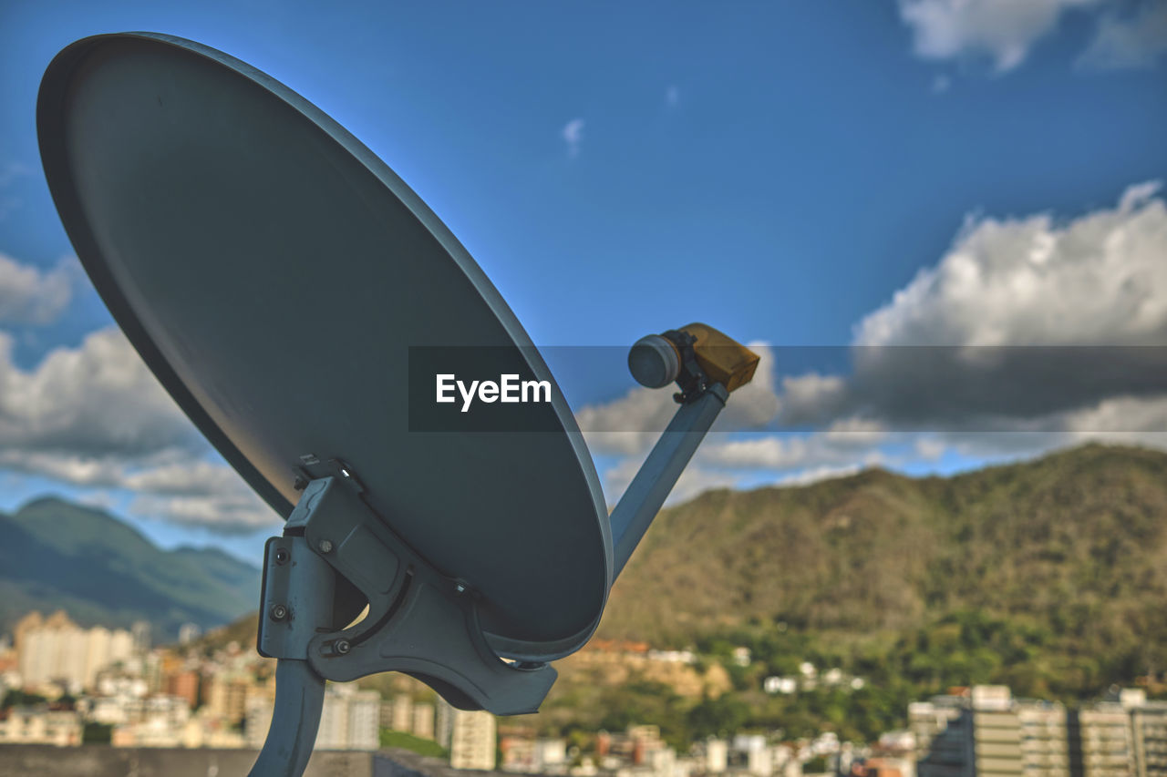 Satellite antenna with city and blue sky background, selective focus