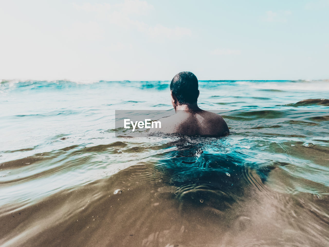 Rear view of shirtless man swimming in sea