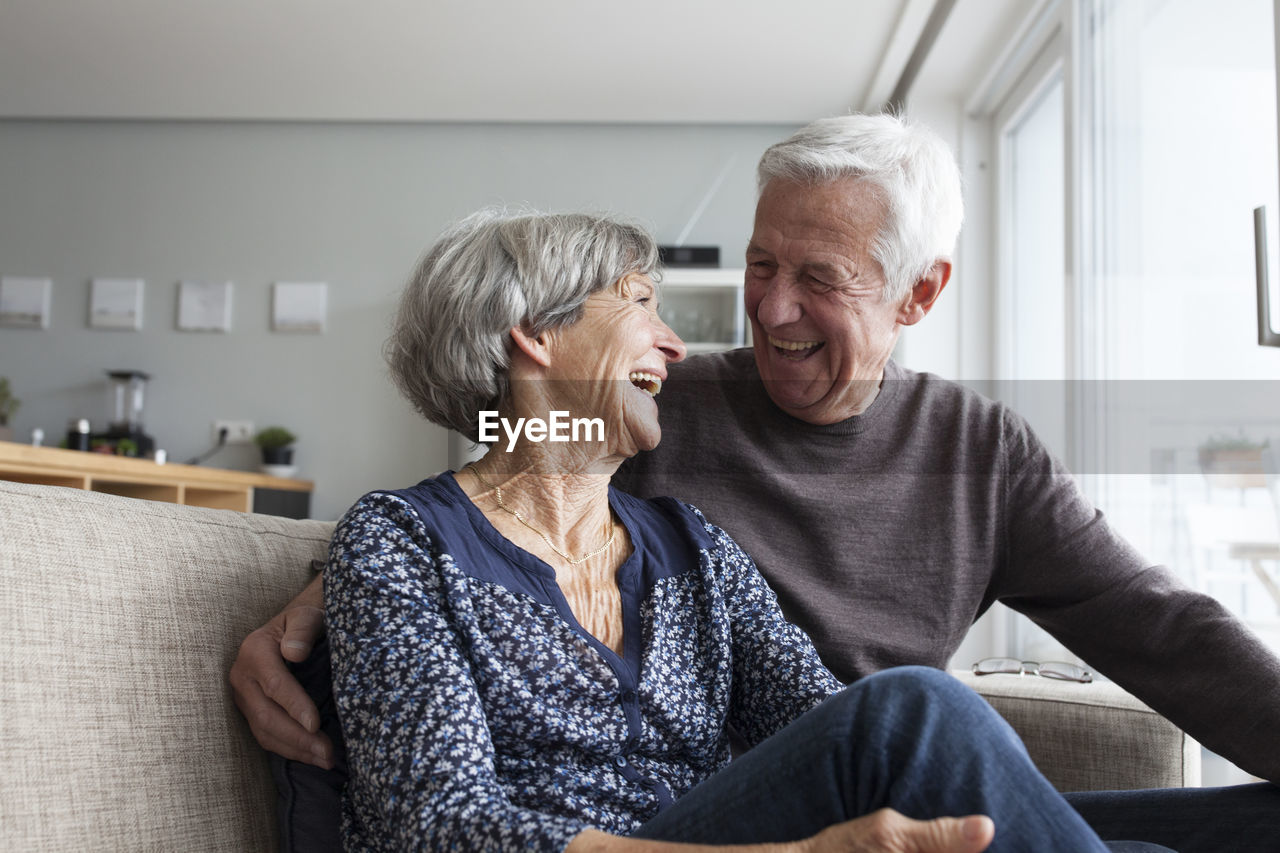 Laughing senior couple sitting together on the couch in the living room