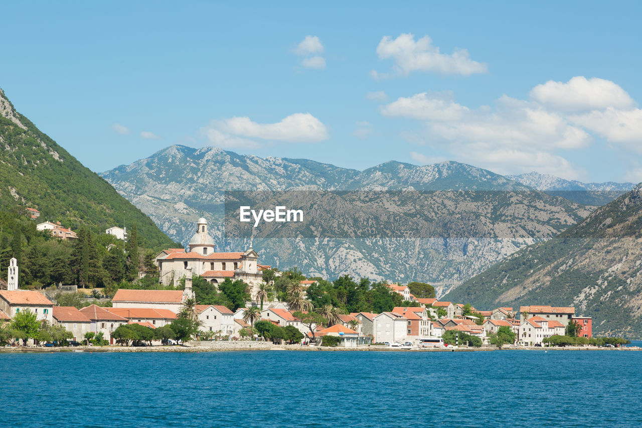 Houses by sea and mountains against sky at kotor bay against sky