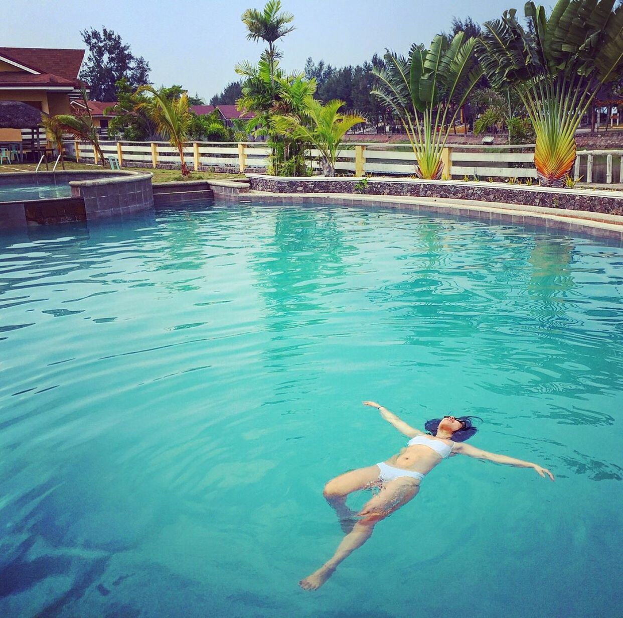 High angle view of sensuous woman in bikini swimming with arms outstretched at pool