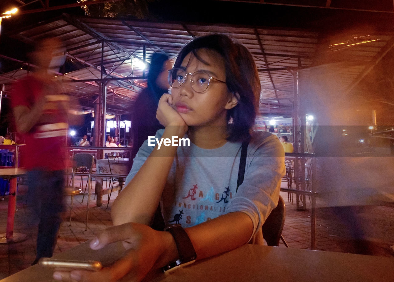 PORTRAIT OF YOUNG WOMAN SITTING IN RESTAURANT