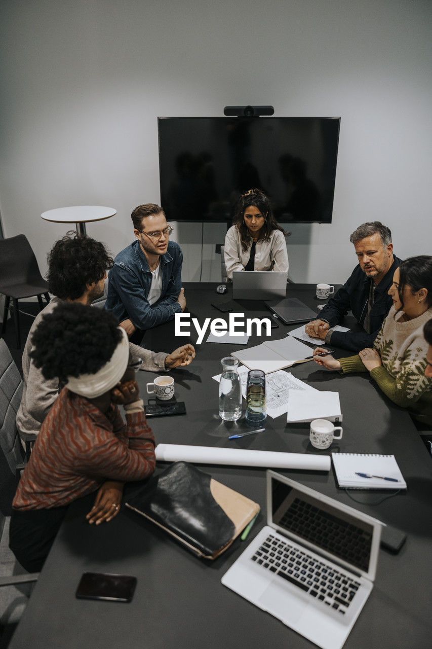 High angle view of multiracial male and female colleagues discussing strategy in board room