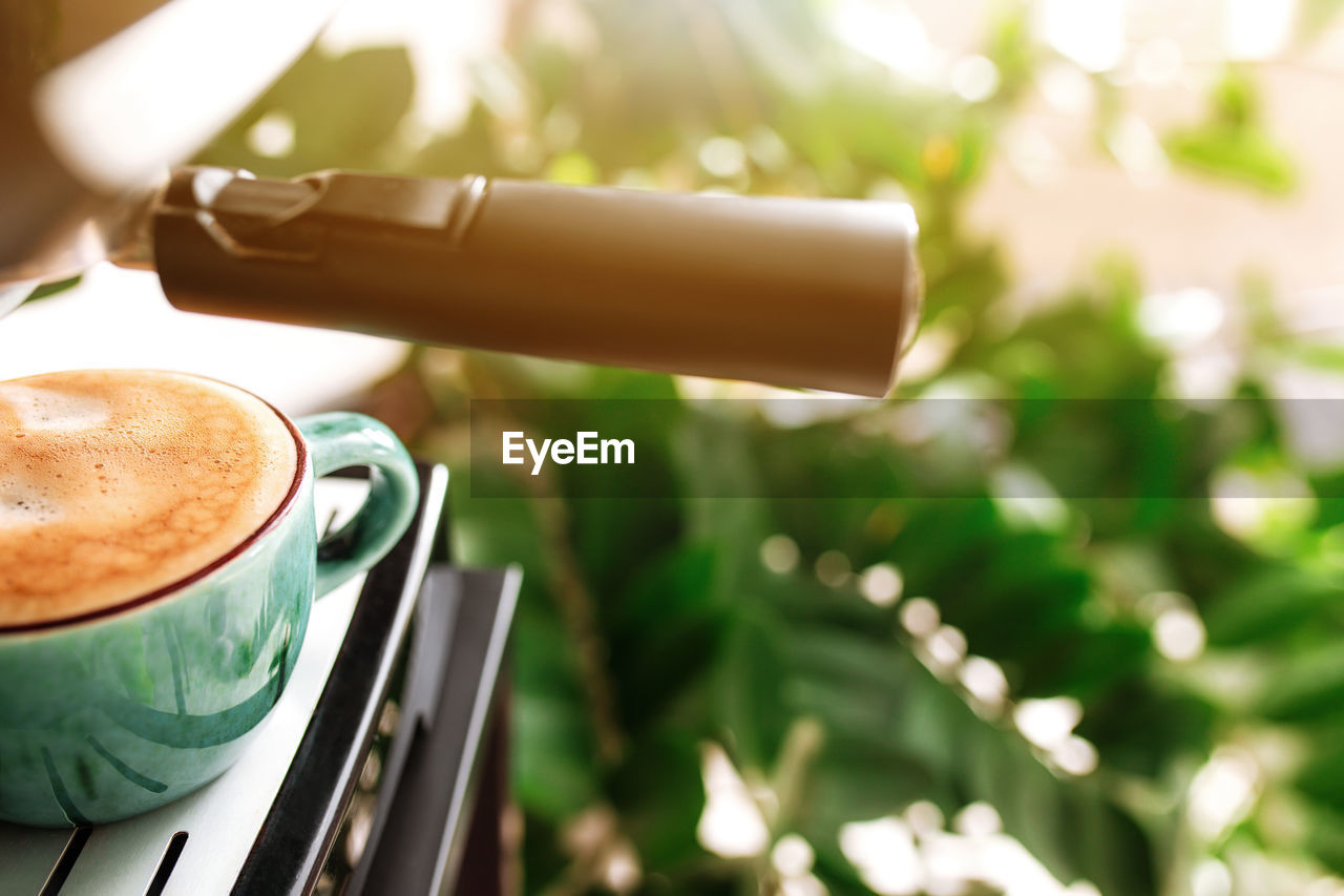 Green coffee cup on coffee maker machine with dispenser. full of espresso, americano or cappuccino