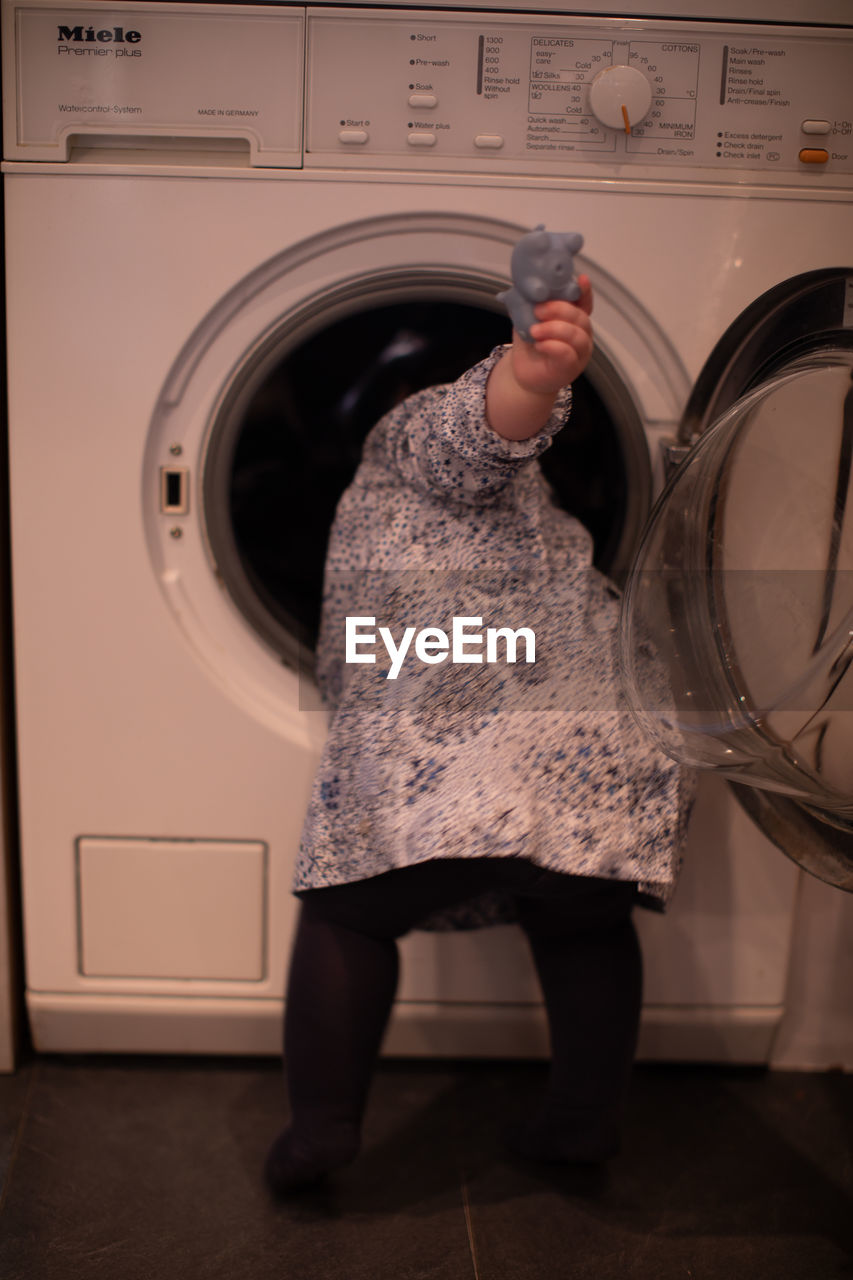 MIDSECTION OF WOMAN STANDING IN FRONT OF MACHINE