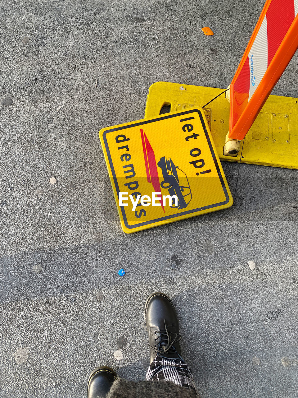 Low section of person standing by warning symbols on road