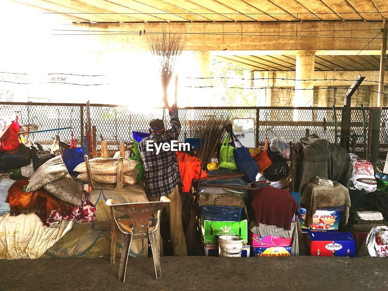 Rear view of man holding broom by objects