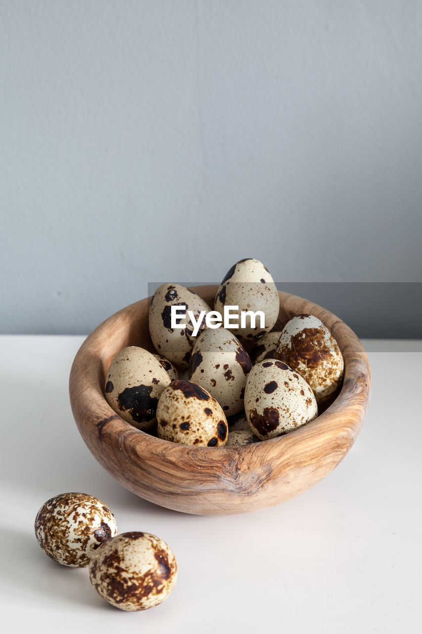 Speckled quail eggs in a rustic wooden bowl