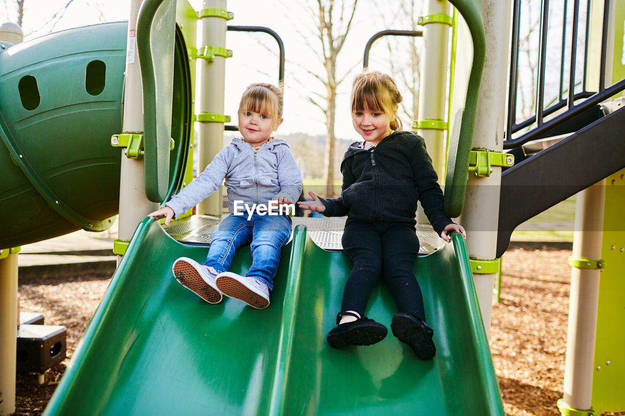 Siblings sitting on swing at park