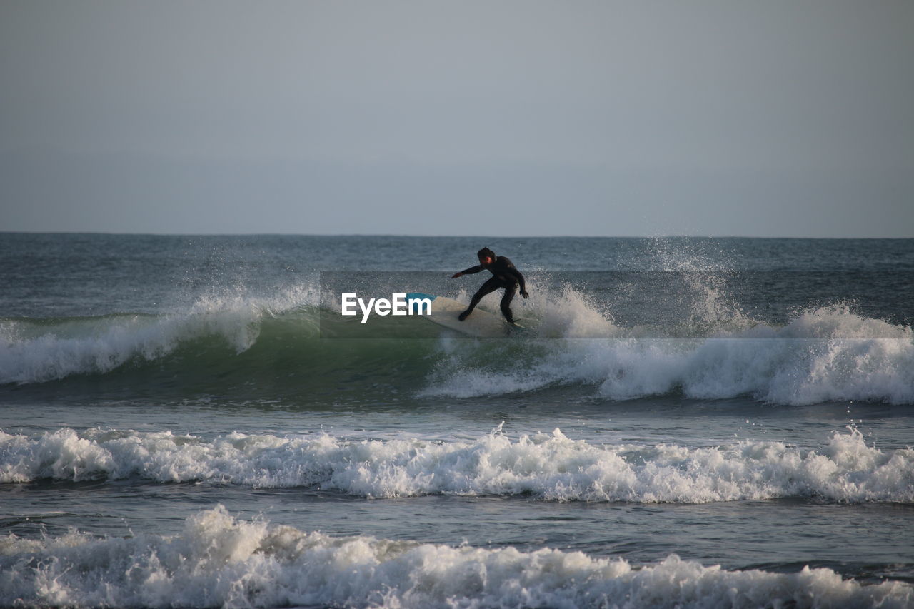 Man surfing in sea against clear sky