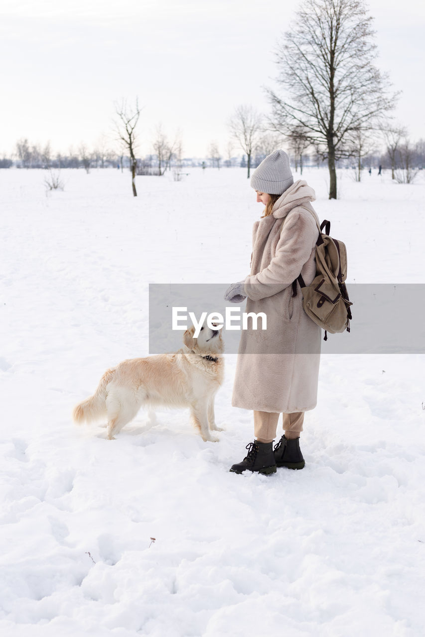 Young beautiful woman and her golden retriever dog having fun in winter.