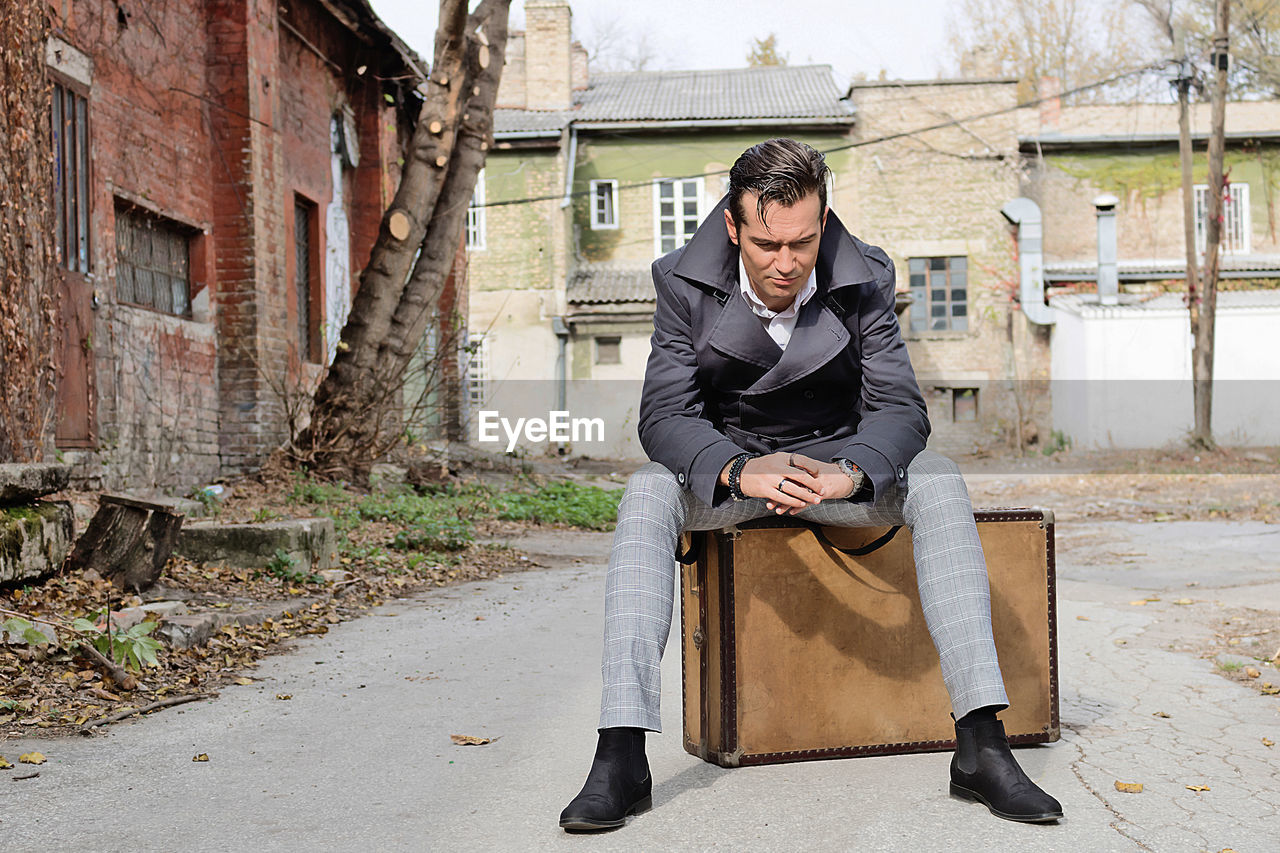 FULL LENGTH OF A YOUNG MAN SITTING ON FLOOR