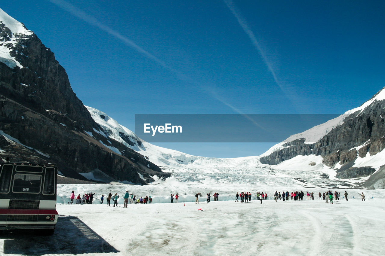 People on snowcapped mountain against sky