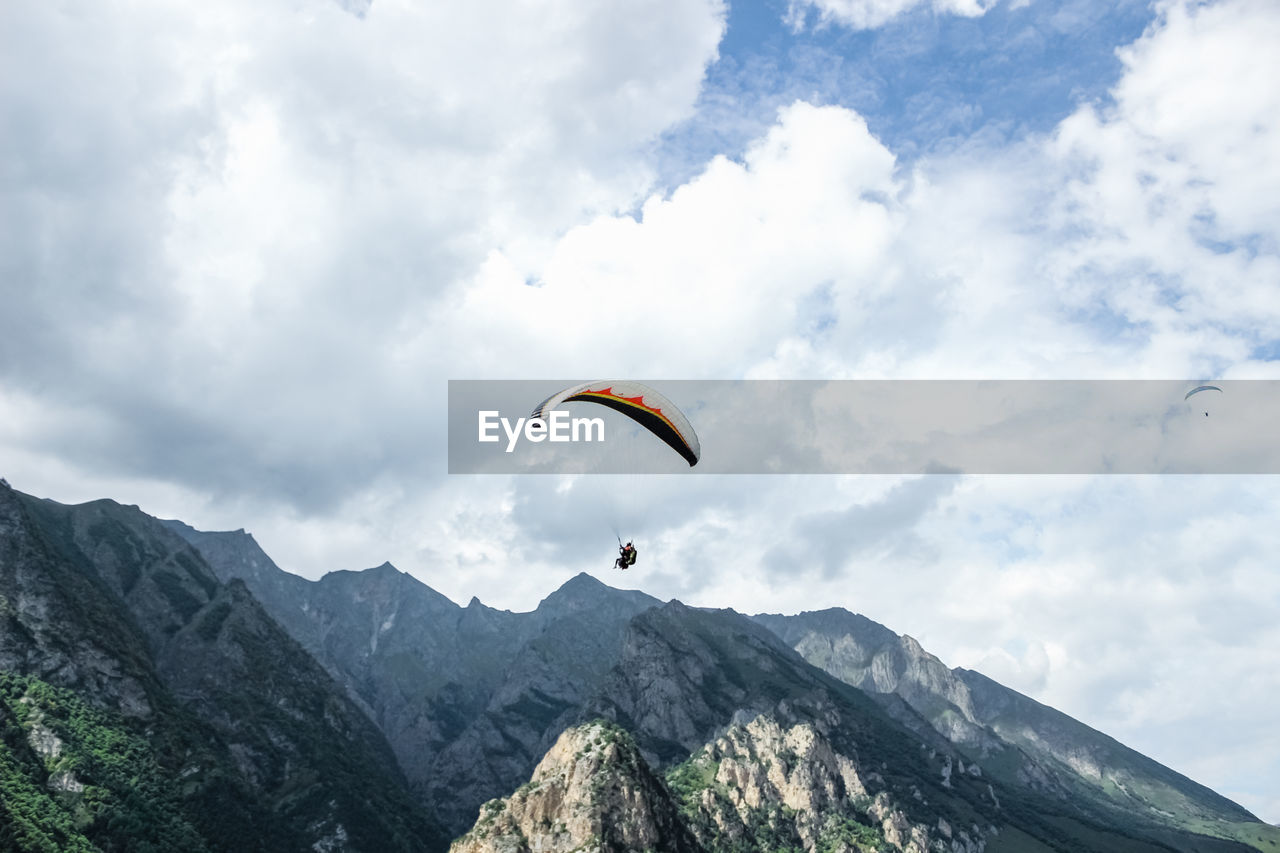 LOW ANGLE VIEW OF PARAGLIDING AGAINST MOUNTAIN