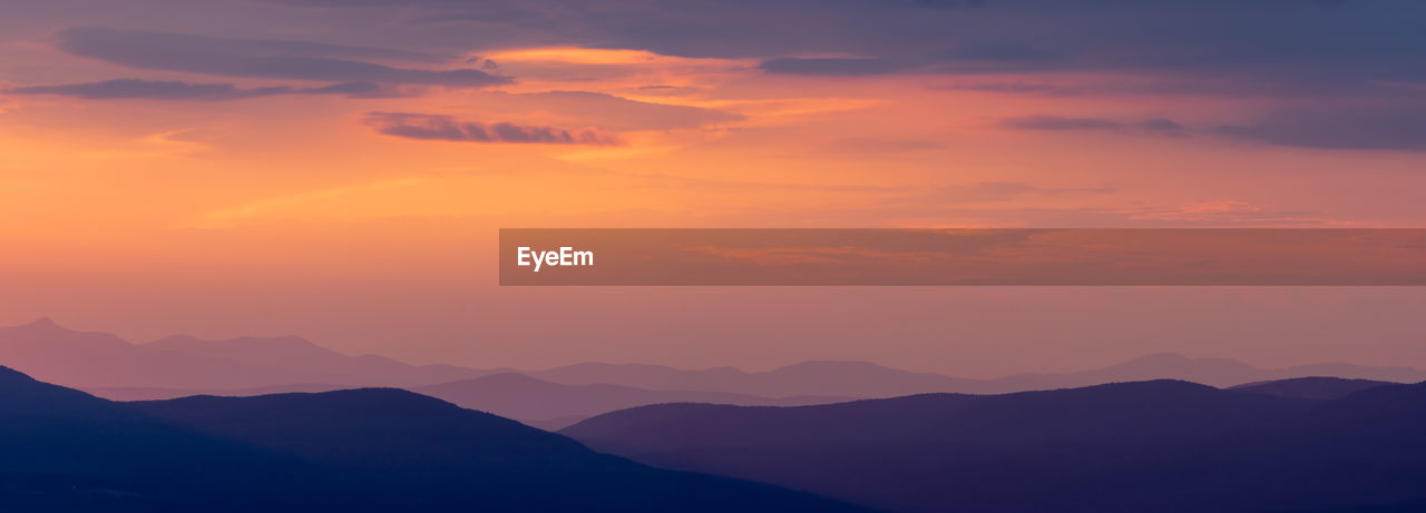 Scenic view of silhouette mountains against romantic sky at sunset