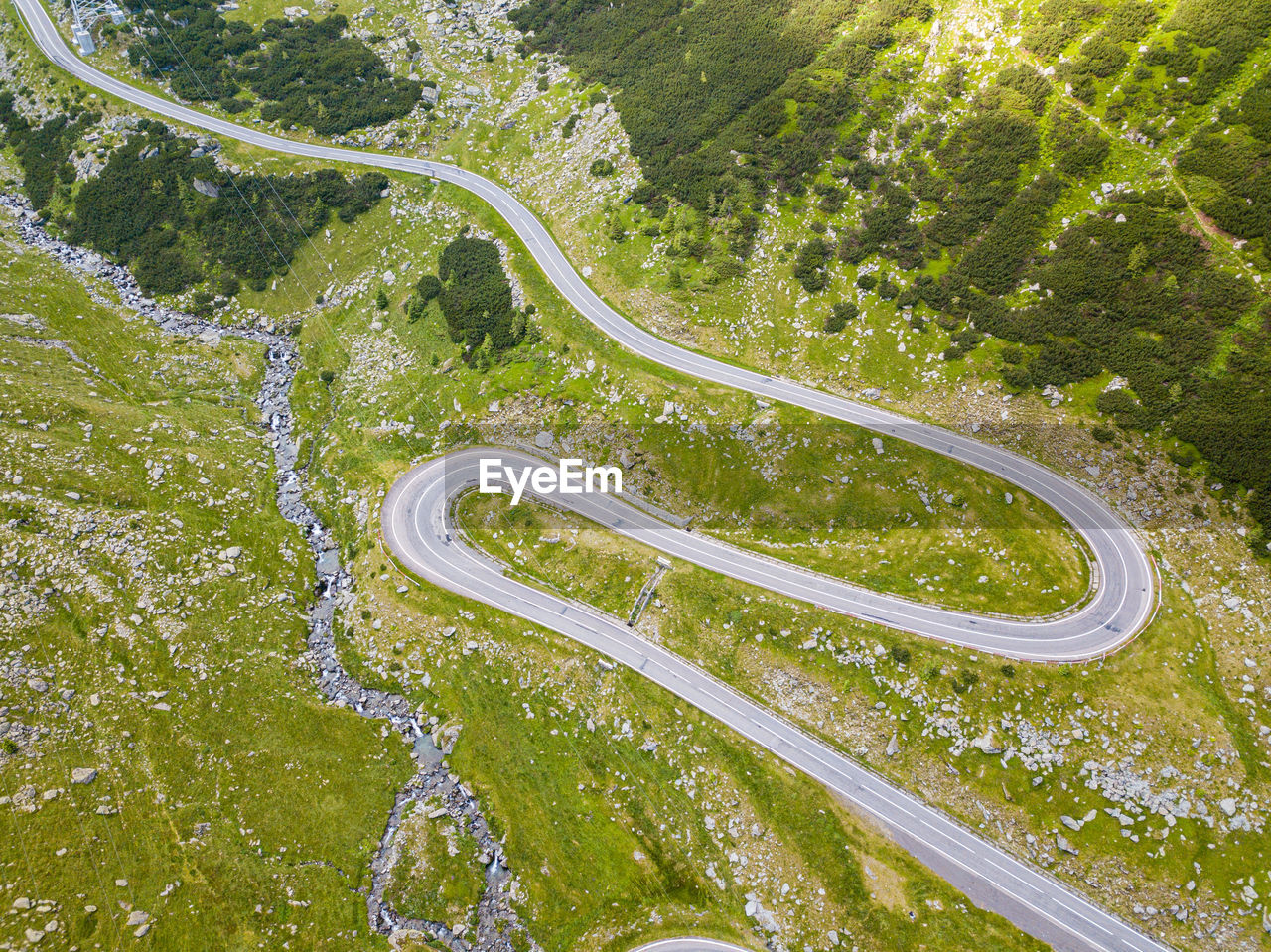 Winding road through the forest, from high mountain pass, in summer time. aerial view