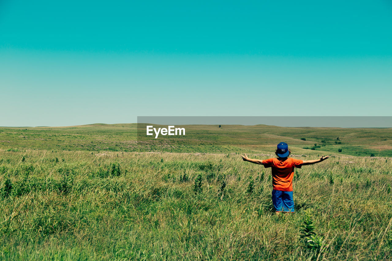 WOMAN STANDING ON GRASSY FIELD