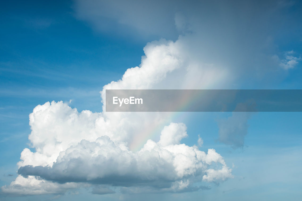 Low angle view of sunlight streaming through clouds