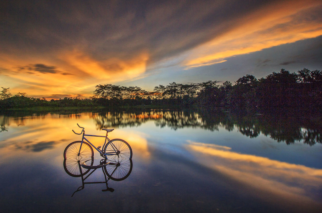 SCENIC VIEW OF LAKE BY TREES AGAINST ORANGE SKY