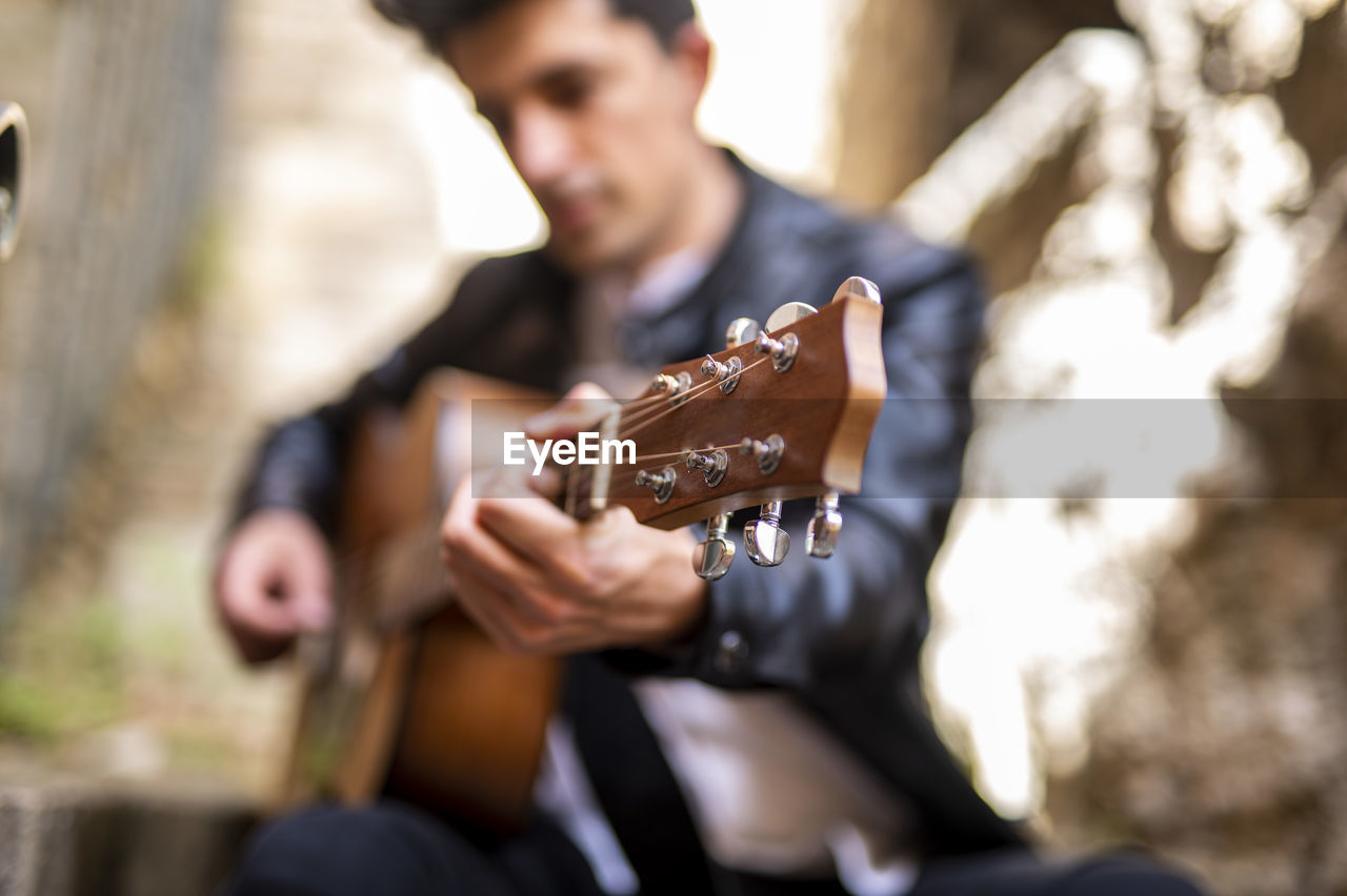 midsection of man playing guitar outdoors